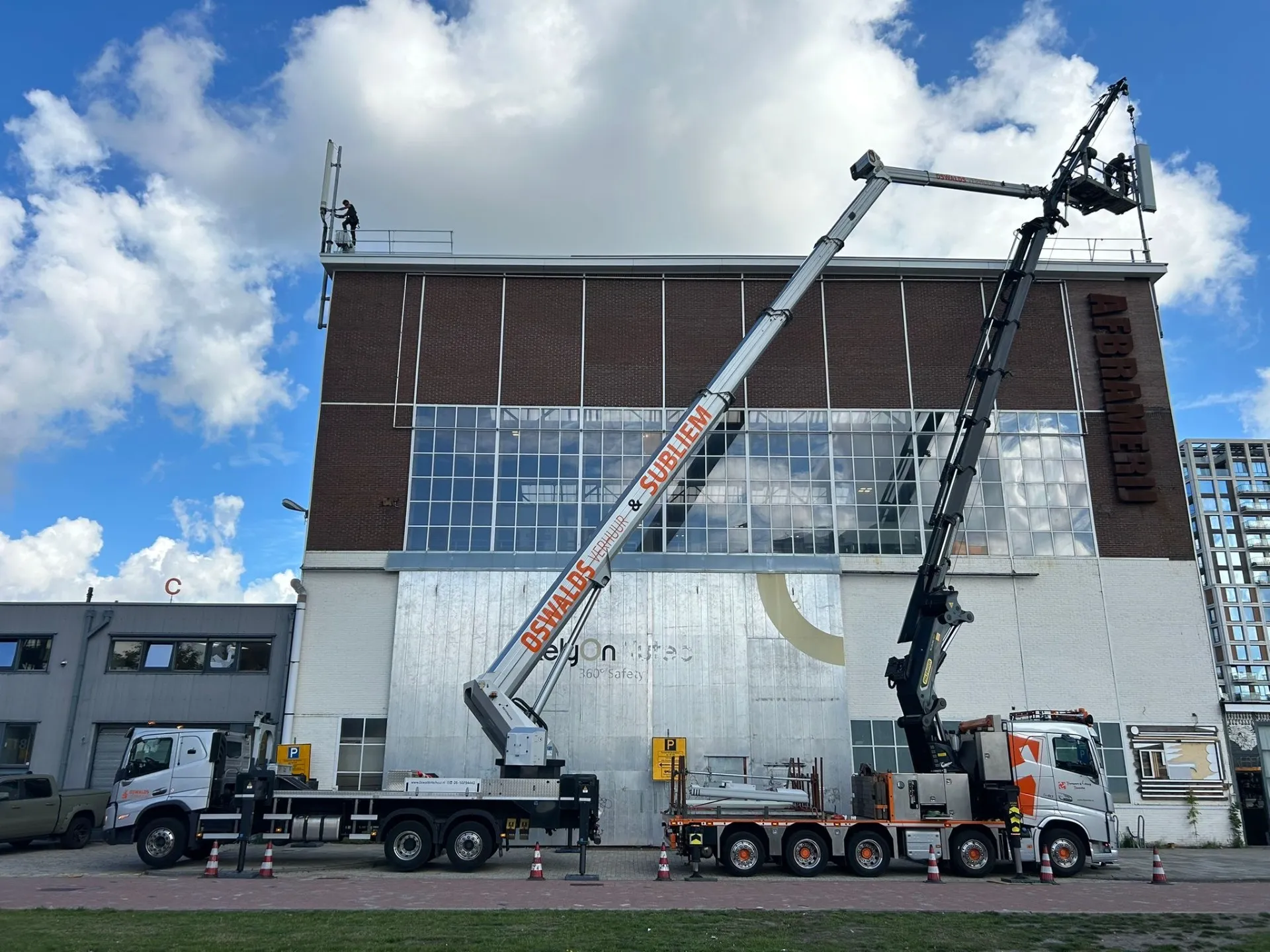 Twee vrachtwagenhoogwerkers bij gebouw